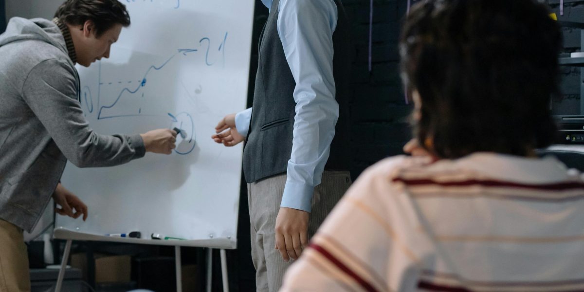 A team engaged in a discussion, using a whiteboard to outline and critically analyze information sources.