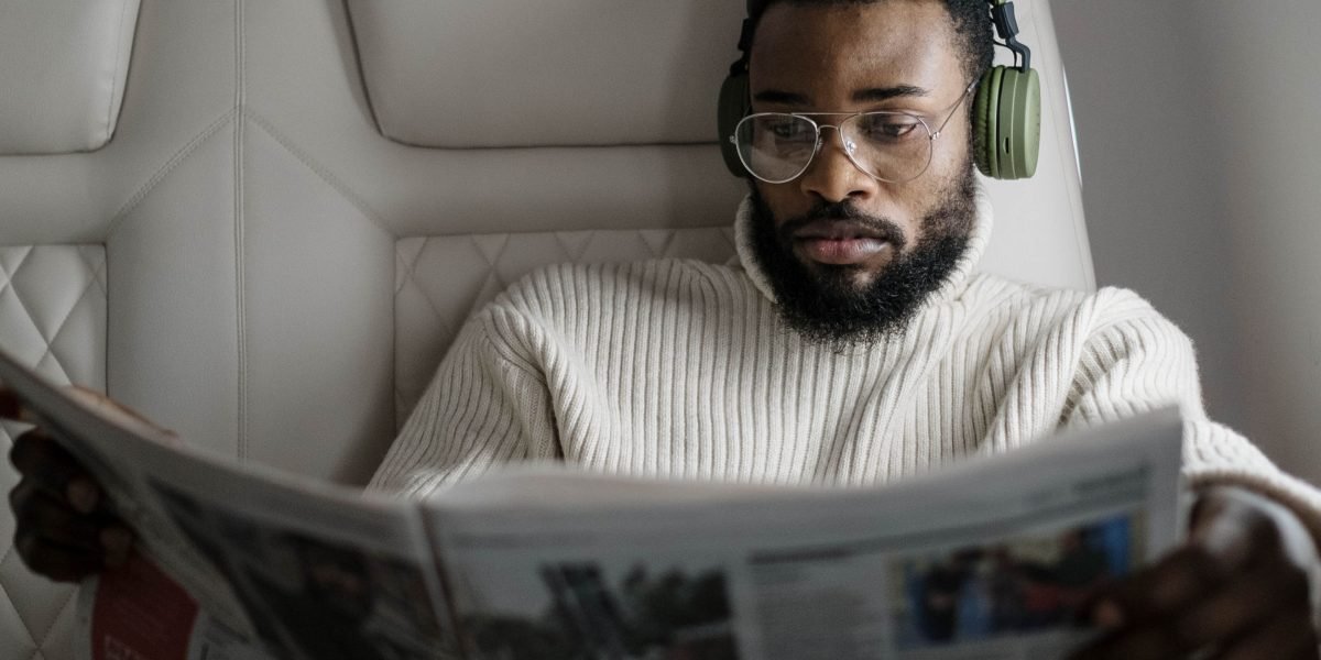 A person engaging with newspaper headlines, pondering the completeness and bias of the reported story.