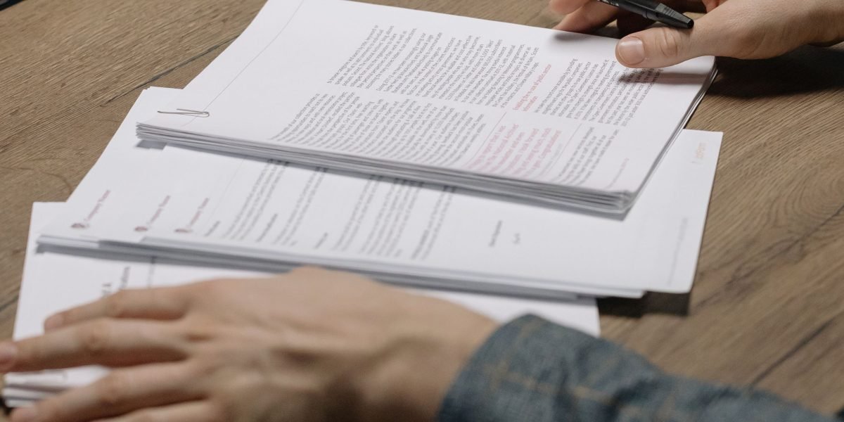 An individual focused on documents or a tablet, carefully assessing the credibility of news sources.