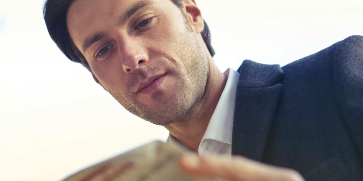 A person engages thoughtfully with a newspaper, reflecting the challenge of discerning trustworthy sources.