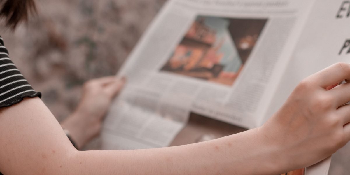 An individual thoughtfully reviewing a newspaper, symbolizing active engagement with local news and informed decision-making.