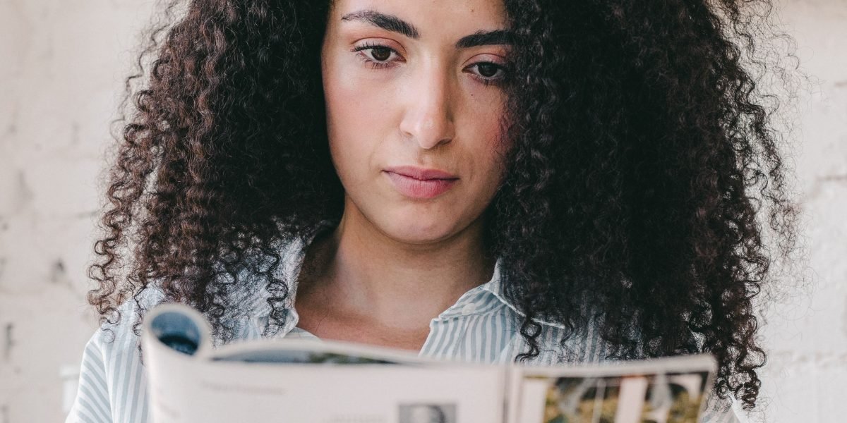 A person engrossed in reading a physical print magazine, emphasizing the tactile and focused reading experience.