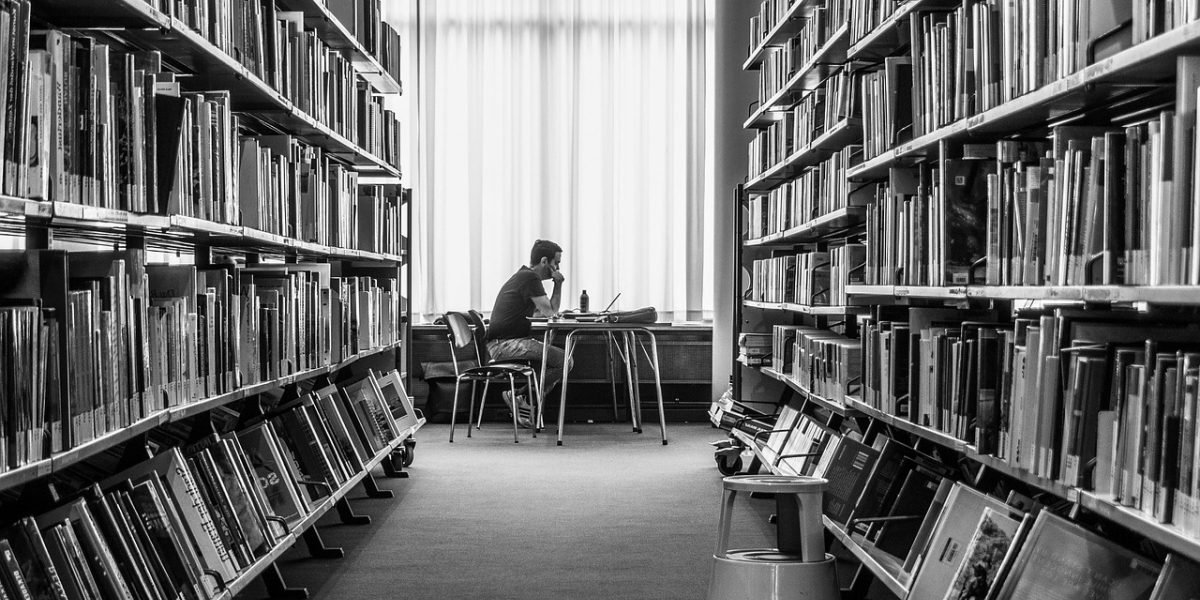 A person conducting research in a library, symbolizing academic analysis of media outlets like the Wiscasset Newspaper.