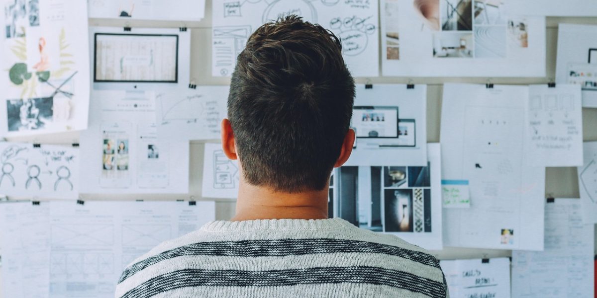 A team of designers collaborating around a whiteboard, sketching out grid-based layouts and discussing design principles.