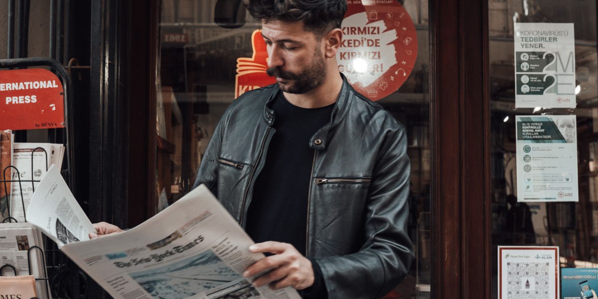 A person engaged in reading a physical newspaper, highlighting the enduring appeal of print media.